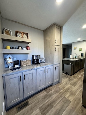 A kitchen with grey cabinets, a coffee machine, and a sink. - Peaceful Farmstead Cottage with Creekside Views Near Iron Station, North Carolina (Iron Station)