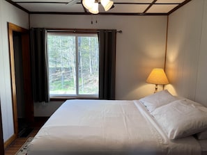 Ein Schlafzimmer mit Bett, Fenster, Lampe und Tür.
