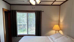 Ein Schlafzimmer mit Bett, Fenster, Lampe und Tür.