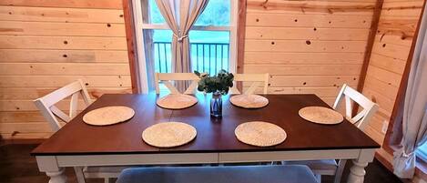 A wooden-paneled room with a dining table, chairs, and a bench.
