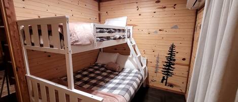 A bunk bed room with wooden walls and a ceiling light.