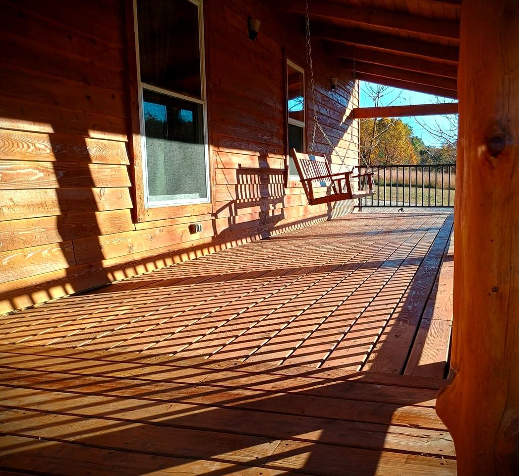 A wooden deck with a railing, a window, and a door.