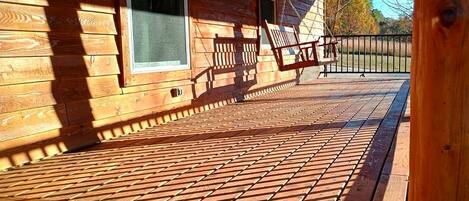 A wooden deck with a railing, a window, and a door.
