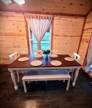 Ein Zimmer mit Holzwandverkleidung, einem Esstisch, Stühlen und einer Bank.