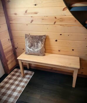 A wooden bench with a deer-shaped pillow against a wooden wall. - Peaceful Woodland Cabin with Balcony & Starry Nights in Steelville, Missouri (Steelville)