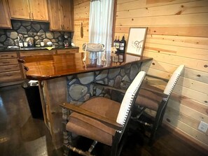 Una cucina rustica con mobili in legno, zoccolo in pietra, un'area bar con sgabelli e un quadro appeso al muro.