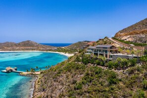 A coastal property with a large house, a dock, and a beach.