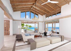 A spacious living area with a high ceiling, large windows, and a view of the ocean.