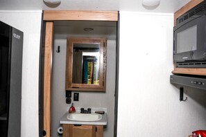 Une petite salle de bain avec un miroir à cadre en bois, un lavabo et un four à micro-ondes.
