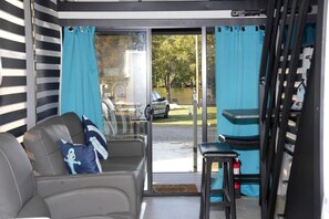 A room with a sliding glass door to a patio, a grey sofa with a pillow, and a small table.