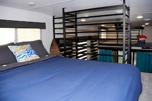 A bunk bed with a blue mattress, a pillow with a wave design, and a wooden ladder.