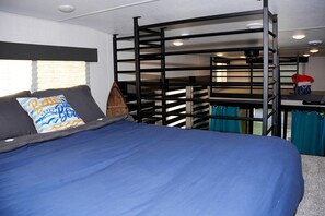 A bunk bed with a blue mattress, a pillow with a wave design, and a wooden ladder.