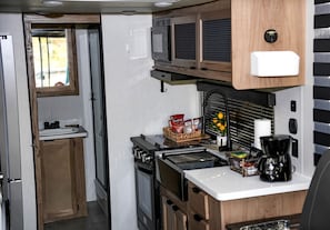 A compact kitchenette with a stove, microwave, and small sink.
