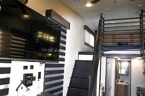 Un interior reducido con una escalera, un televisor montado y un panel de control.