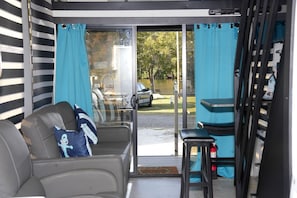 A room with a sliding glass door to a patio, a grey sofa with a pillow, and a small table.