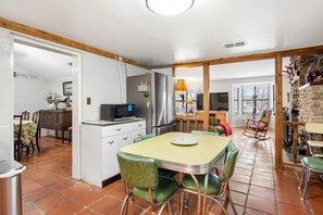 A spacious kitchen with a dining area, a built-in microwave, and a refrigerator. - Riverbank Escape for Families and Friends with Ping Pong, Mrs. Pac-Man, and Cozy Den in Kerrville, Texas (Kerrville)