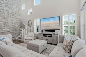 Ein Wohnzimmer mit SteinsĂ€ule, einem Flachbildfernseher, einem weiĂen Sessel, einem Sofa und einer Treppe.