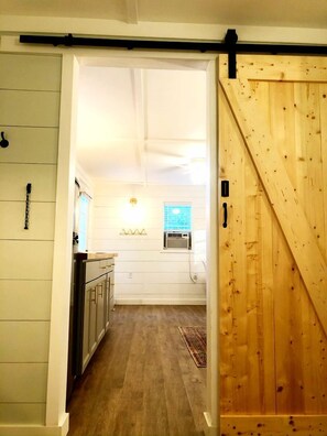A kitchen with white walls, wooden cabinets, and a sliding barn door.