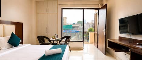 Ein Hotelzimmer mit Bett, Fernseher, Schreibtisch, Stuhl, einem Balkon mit Blick und einem Kleiderschrank.