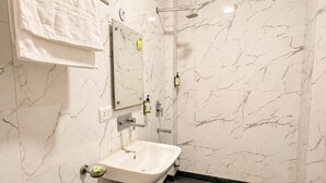 A bathroom with a white marble wall, a pedestal sink, a handheld showerhead, and a towel rack. - The Milford Noida (Noida)