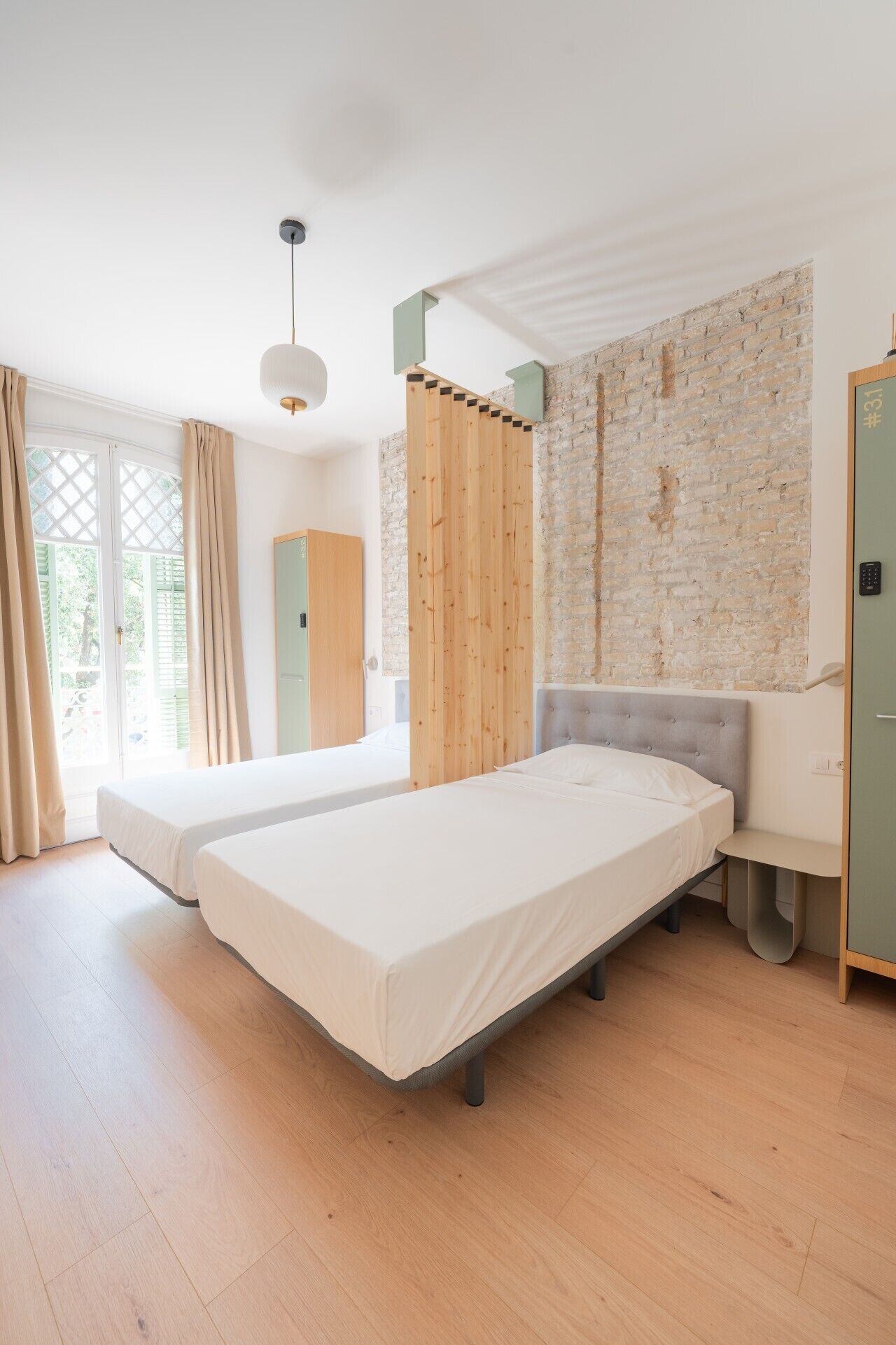 Une chambre moderne avec deux lits, un mur en briques et une cloison en bois.