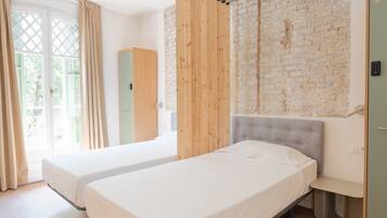 Une chambre moderne avec deux lits, un mur en briques et une cloison en bois.