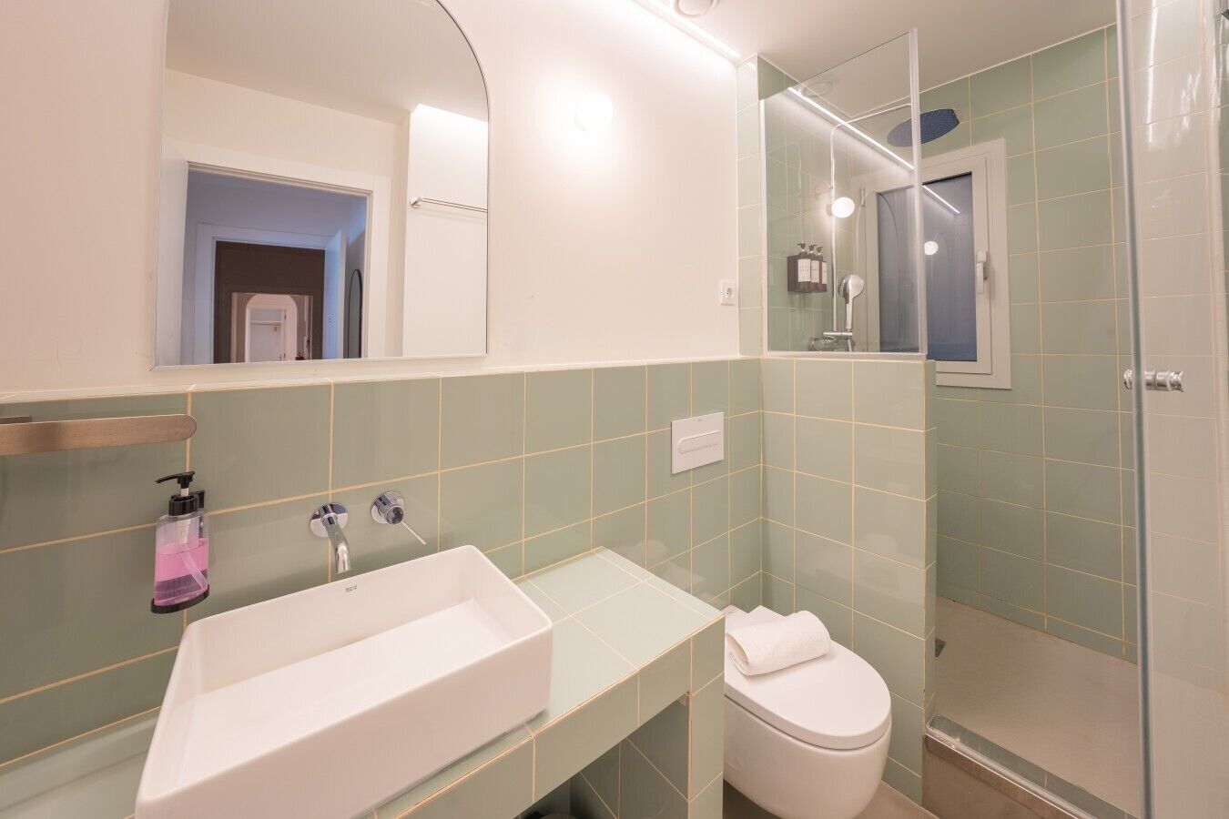 Un baño moderno con un lavamanos rectangular, un inodoro y una ducha con mampara de vidrio.