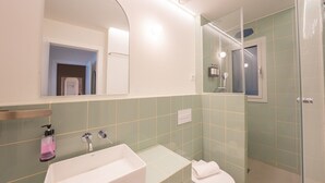Ein modernes Badezimmer mit einem rechteckigen Waschbecken, einer Toilette und einer Duschkabine aus Glas.