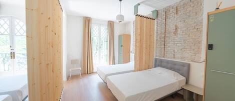 Une chambre avec deux lits, une armoire en bois, une porte verte et un mur en briques.