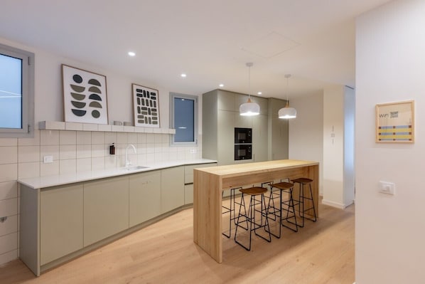 A modern kitchen with a central island, bar stools, and a window.
