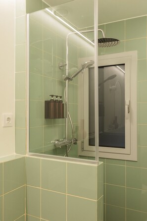 Een douche met glazen wanden, een witte deur en een handdoekrek met flesjes.