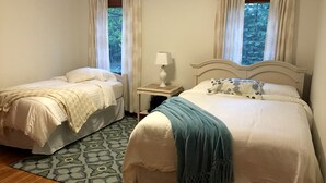 Een slaapkamer met twee bedden, een nachtkastje, een lamp en een kamerkleed met een patroon.
