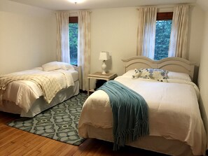 Een slaapkamer met twee bedden, een nachtkastje, een lamp en een kamerkleed met een patroon.