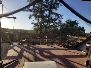 A wooden deck with a view of a fenced area and trees.