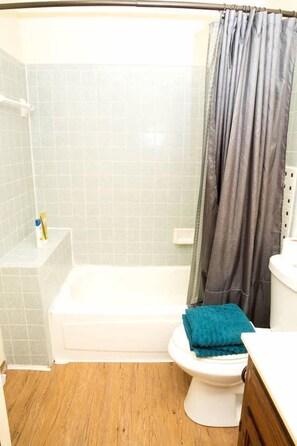 Un baño con bañera, inodoro y cortina de ducha.