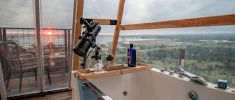 Une pièce dotée d’une grande fenêtre, d’un télescope et d’un jacuzzi.