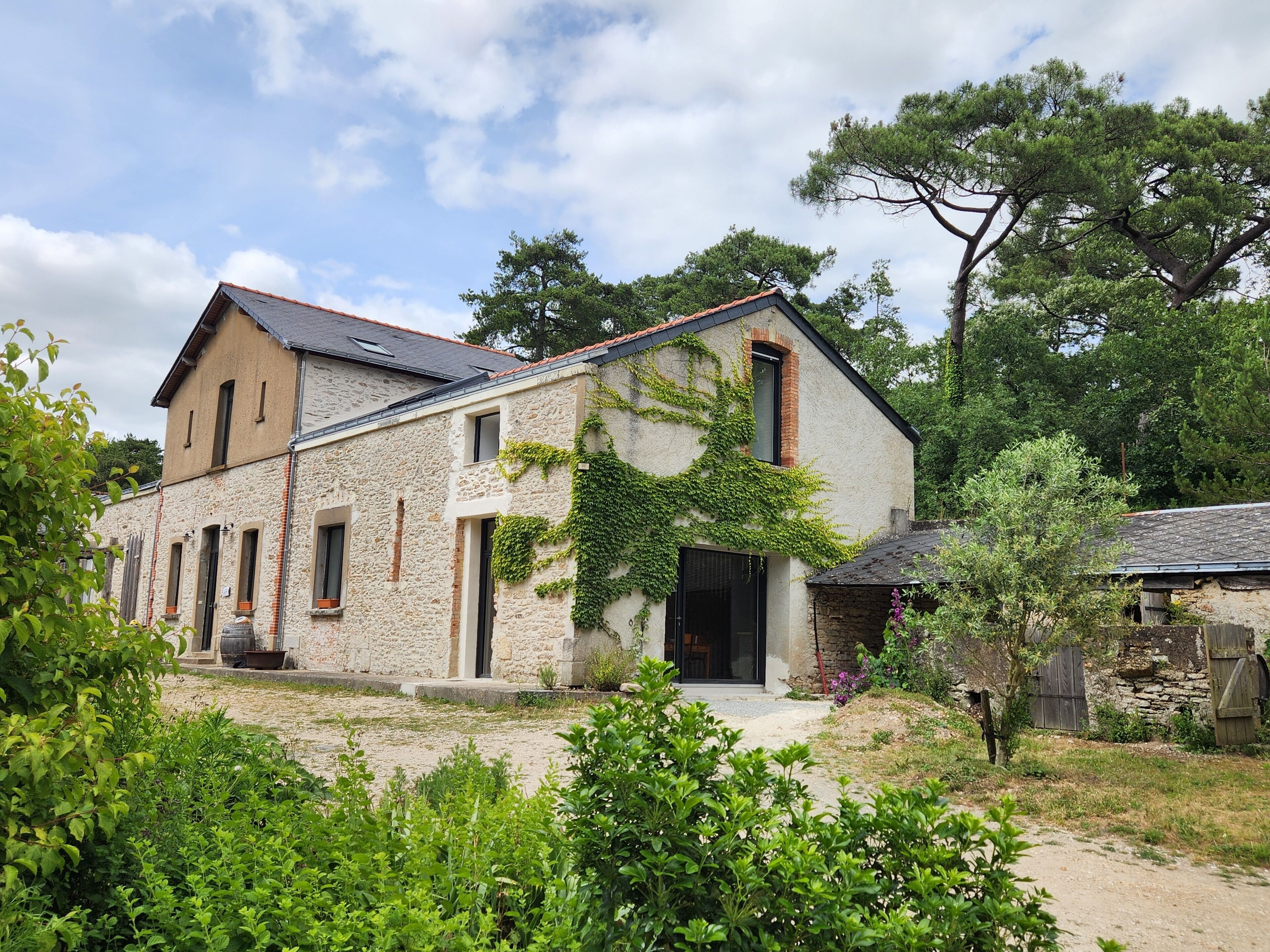A rustic stone building with a sloped roof, a large door, and a small porch.