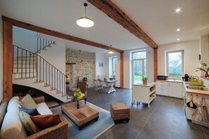 Un vaste espace de vie comprenant un escalier, un coin repas et une cuisine équipée d’appareils électroménagers modernes.
