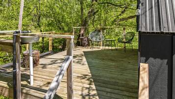 A wooden deck with a metal railing, a chair, and a small table.