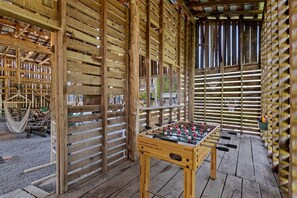 Een houten constructie met een tafelvoetbalspel, een hangmat en een basketbalring.