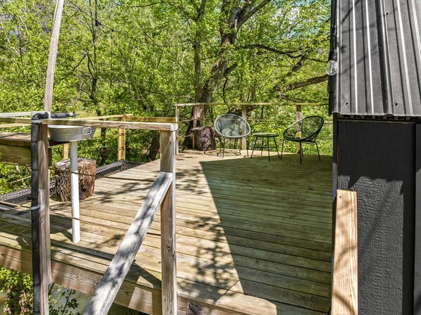 Eine Holzterrasse mit Metallgeländer, einem Stuhl und einem kleinen Tisch.