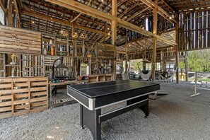 Un espacio interior con mesa de ping pong, palés de madera y decoración rústica.
