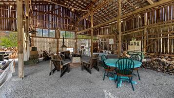 A rustic wooden structure with a covered patio area featuring tables and chairs, a hanging lamp, and a view of the outdoors.
