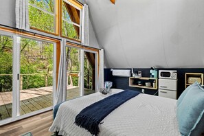 Un dormitorio con una cama grande, una terraza de madera y una kitchenette con electrodomésticos modernos.