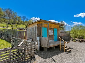 Una cabana de fusta amb una porta blava, un petit porxo i un senyal que indica que és un lavabo i vàter.
