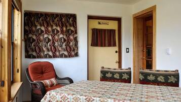 Una habitación con una cama, una silla, una mesa y un tapiz decorativo en la pared.