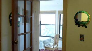 Una habitación con puerta de madera, una silla, un tapete y un espejo en la pared.