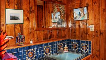 Un baño de madera con lavamanos de azulejos azules, cuadros enmarcados y pared de madera.