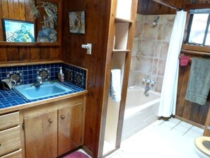 Une salle de bain avec un meuble-lavabo en bois, un évier, une baignoire et une douche.