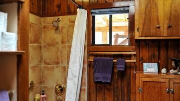 A bathroom with wooden paneling, a bathtub, a window, and a striped rug.